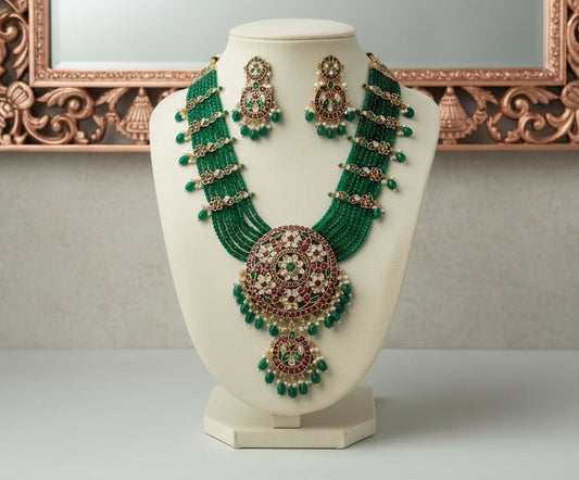 Green and red beaded necklace and earrings on a mannequin bust against a gray background
