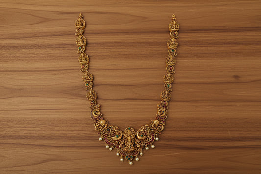 Ornate gold necklace on a light green background