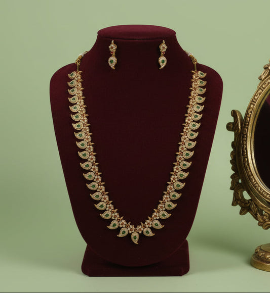 Jewelry set with necklace and earrings on a mannequin bust against a green background