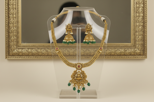 Gold necklace and earrings on a mannequin bust with a beige background