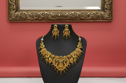 Gold necklace and earrings on a black stand against a red background