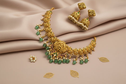 Gold necklace with emeralds and pearls on a beige fabric background
