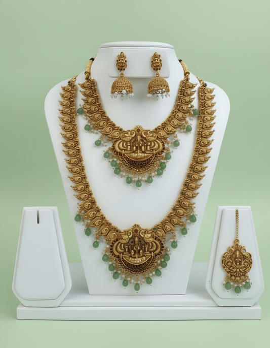 Bridal Jewelry set including obe short and long necklaces and earrings on a white stand against a light blue background