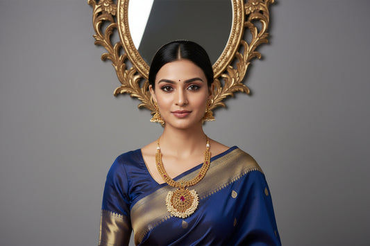 Woman wearing a blue saree with gold jewelry on a gray background