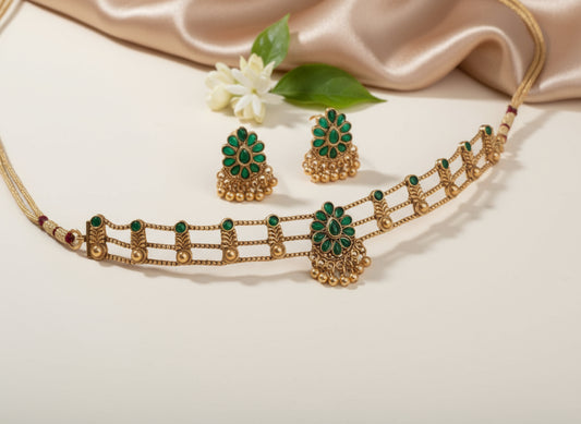 Gold necklace with green gemstones on a beige fabric background
