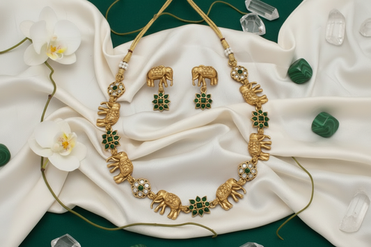 Gold necklace with elephant designs on a white background