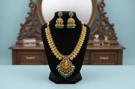 Gold necklace and earrings set on a black stand with a gray background