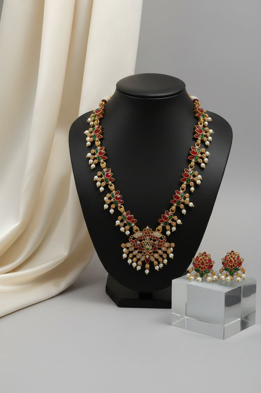 Ornate necklace on a black stand with earrings on a gray surface