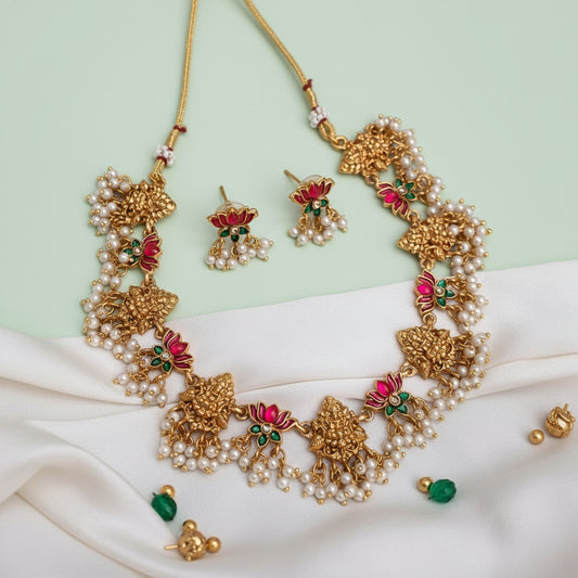 Gold necklace with pearls and pink flowers on a white fabric background
