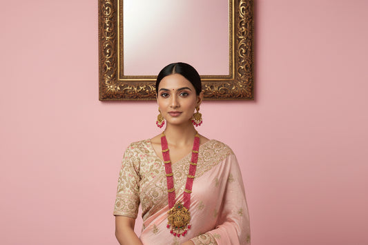 Gold necklace with pink beads and matching earrings on a white fabric background