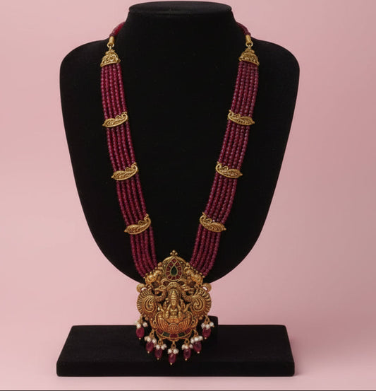 Ornate pink beaded necklace with gold accents on a white background