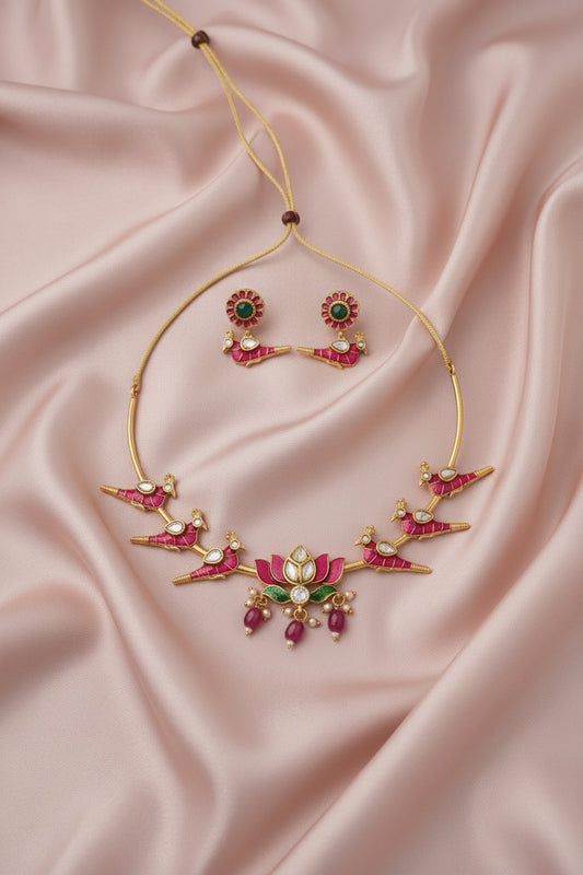 Gold necklace with pink and green gemstones on a beige fabric background
