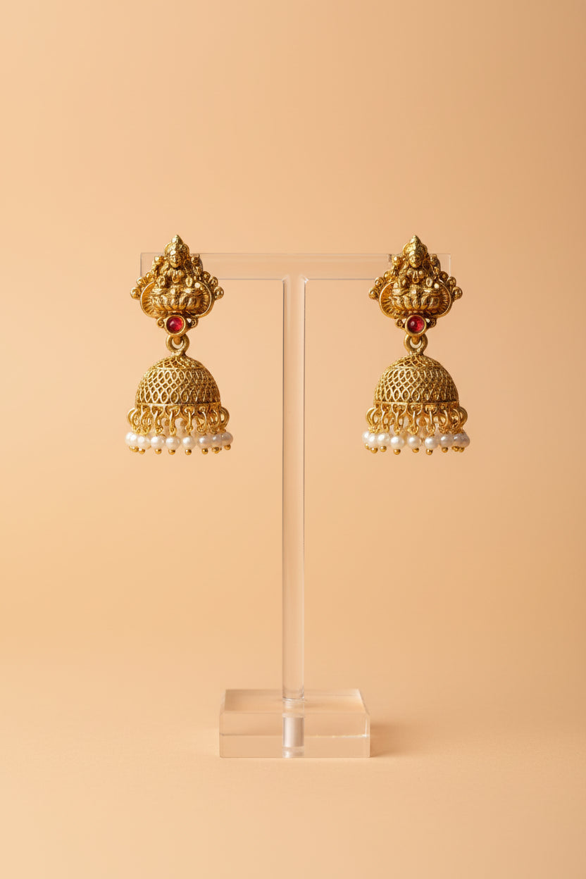 A necklace set features a goddess pendant framed with vibrant stones and pearl clusters, paired with ornate jhumkas.