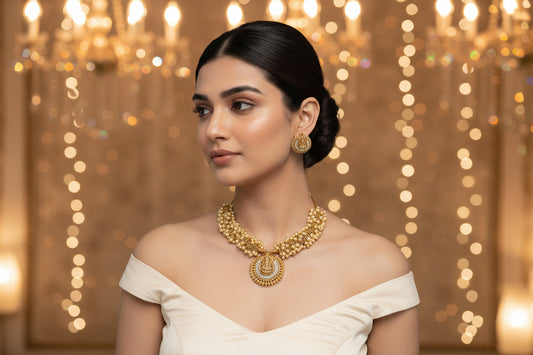 Woman wearing a gold necklace and earrings on a gray background