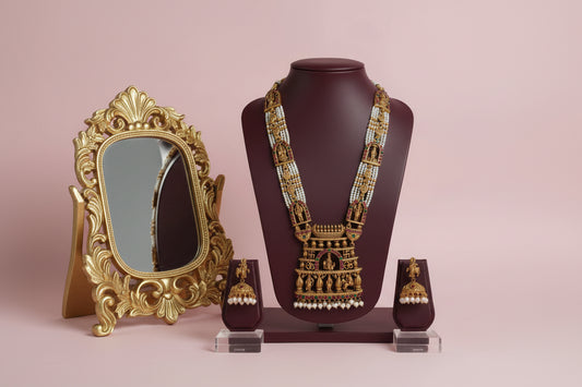 Gold necklace with matching earrings on a mannequin bust against a pink background