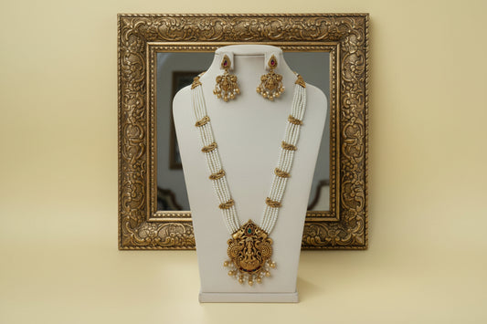 Gold necklace and earrings on a white stand with a pink background