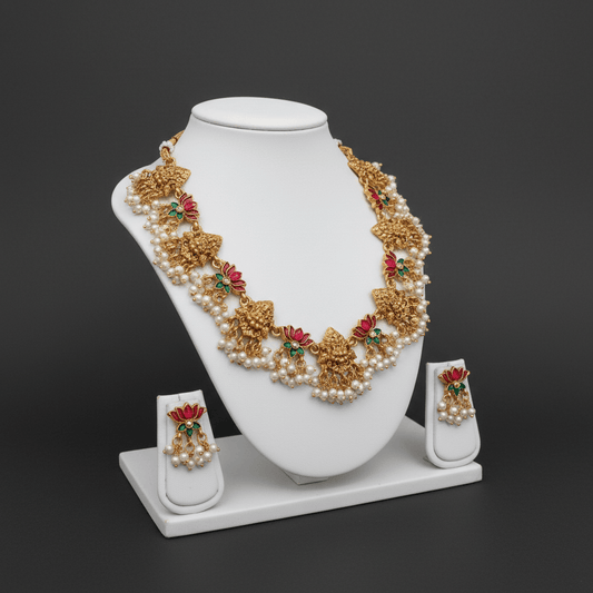 Necklace set featuring gold Lakshmi motifs with pink and green enamel lotus accents, finished with clusters of pearls.