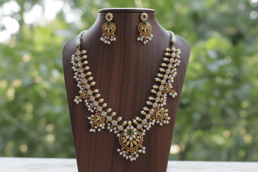 This exquisite gold-hued necklace and earring ensemble features red and green stones, delicate pearl drops.