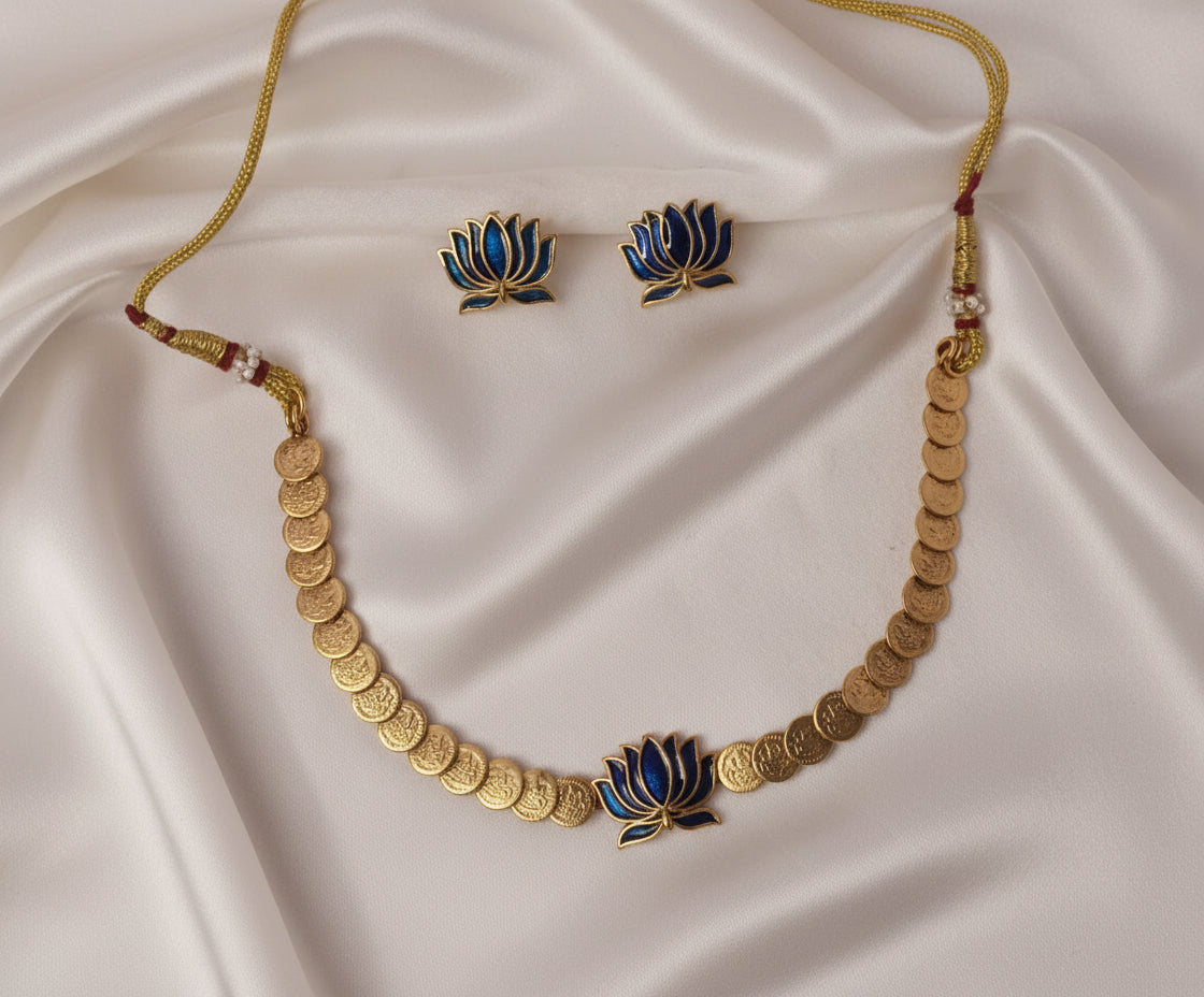 Gold necklace and earrings with lotus design on a satin fabric background