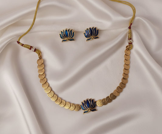 Gold necklace and earrings with lotus design on a satin fabric background