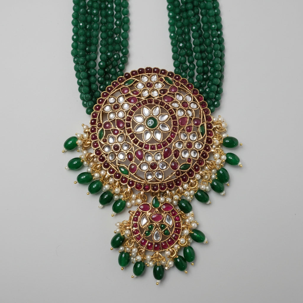 Ornate necklace with green beads and gold and red accents on a gray background