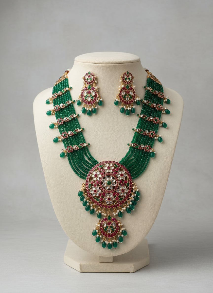 Green and red beaded necklace and earrings on a mannequin bust against a gray background