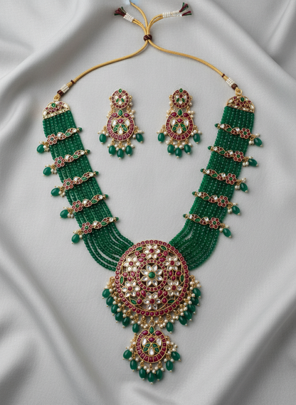 Green beaded necklace and earrings set on a white fabric background