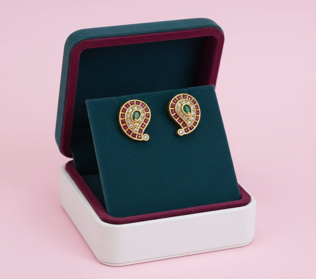 Pair of gold earrings with stones in a jewelry box on a pink background