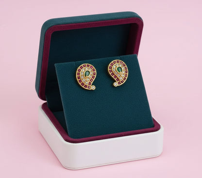 Pair of gold earrings with stones in a jewelry box on a pink background