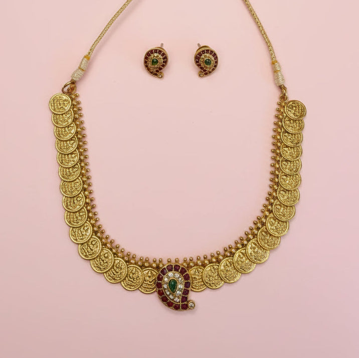 Gold necklace and earrings on a white fabric background