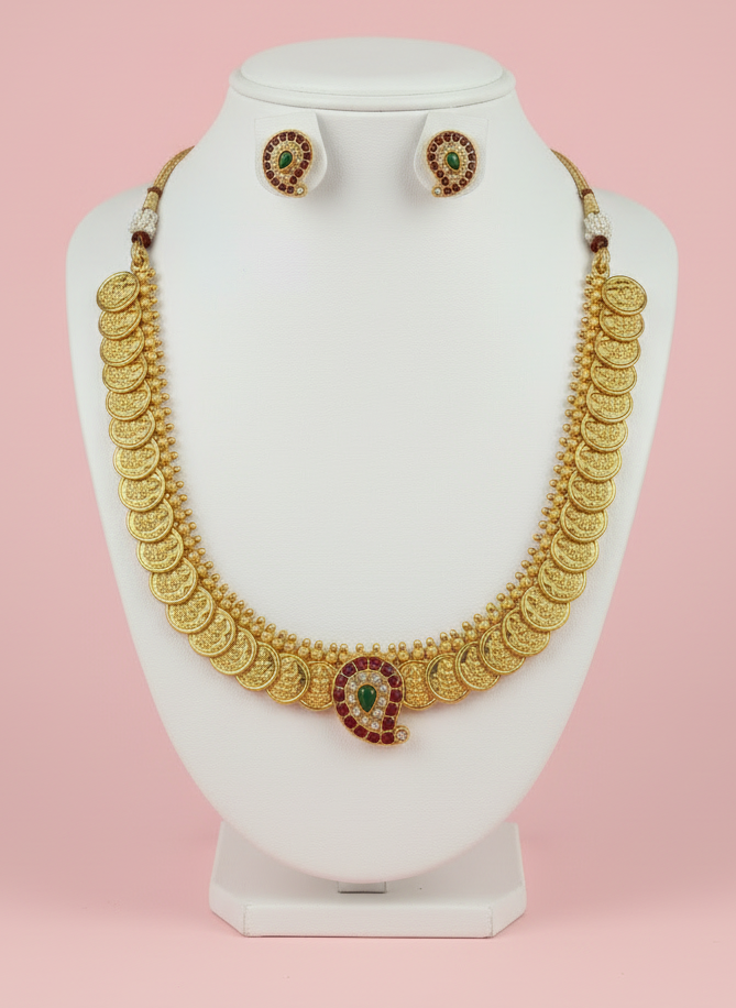 Gold necklace and earrings on a white mannequin bust against a pink background