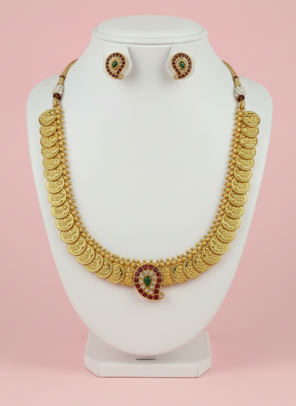 Gold necklace and earrings on a white mannequin bust against a pink background
