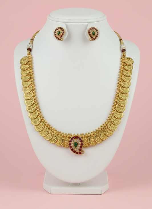 Gold necklace and earrings on a white mannequin bust against a pink background