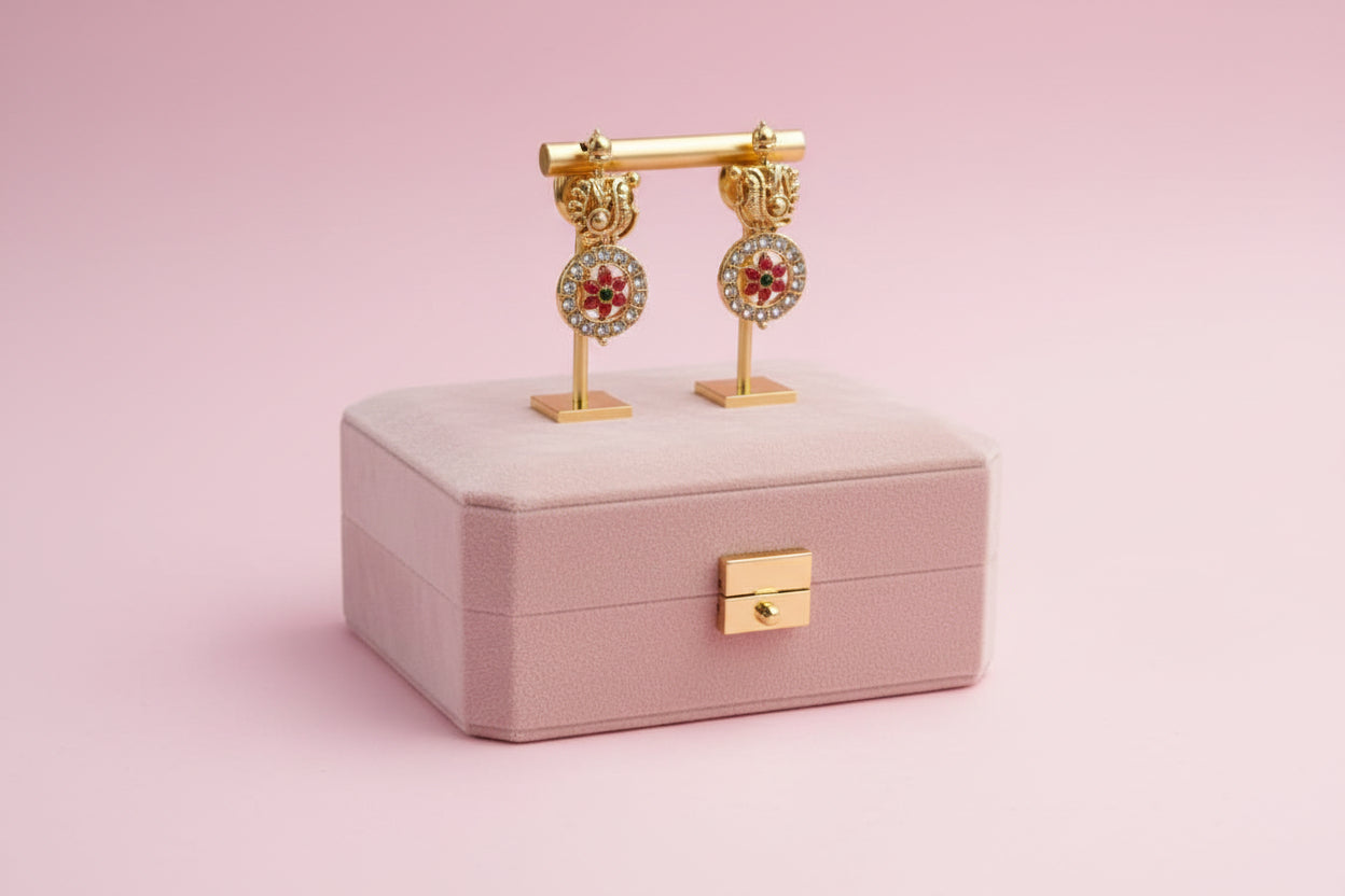 Gold earrings on a pink jewelry box with a pink background