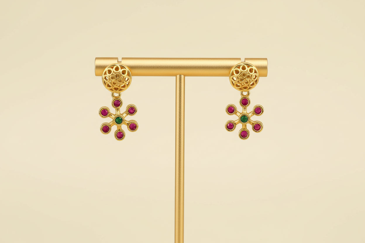Gold earrings with gemstones on a beige background