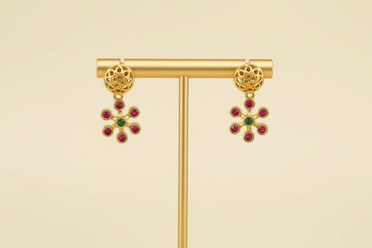 Gold earrings with gemstones on a beige background