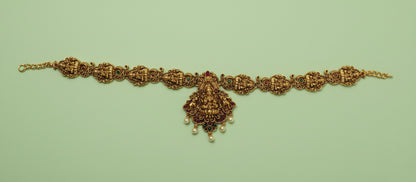 Gold bracelet with intricate design on a light green background