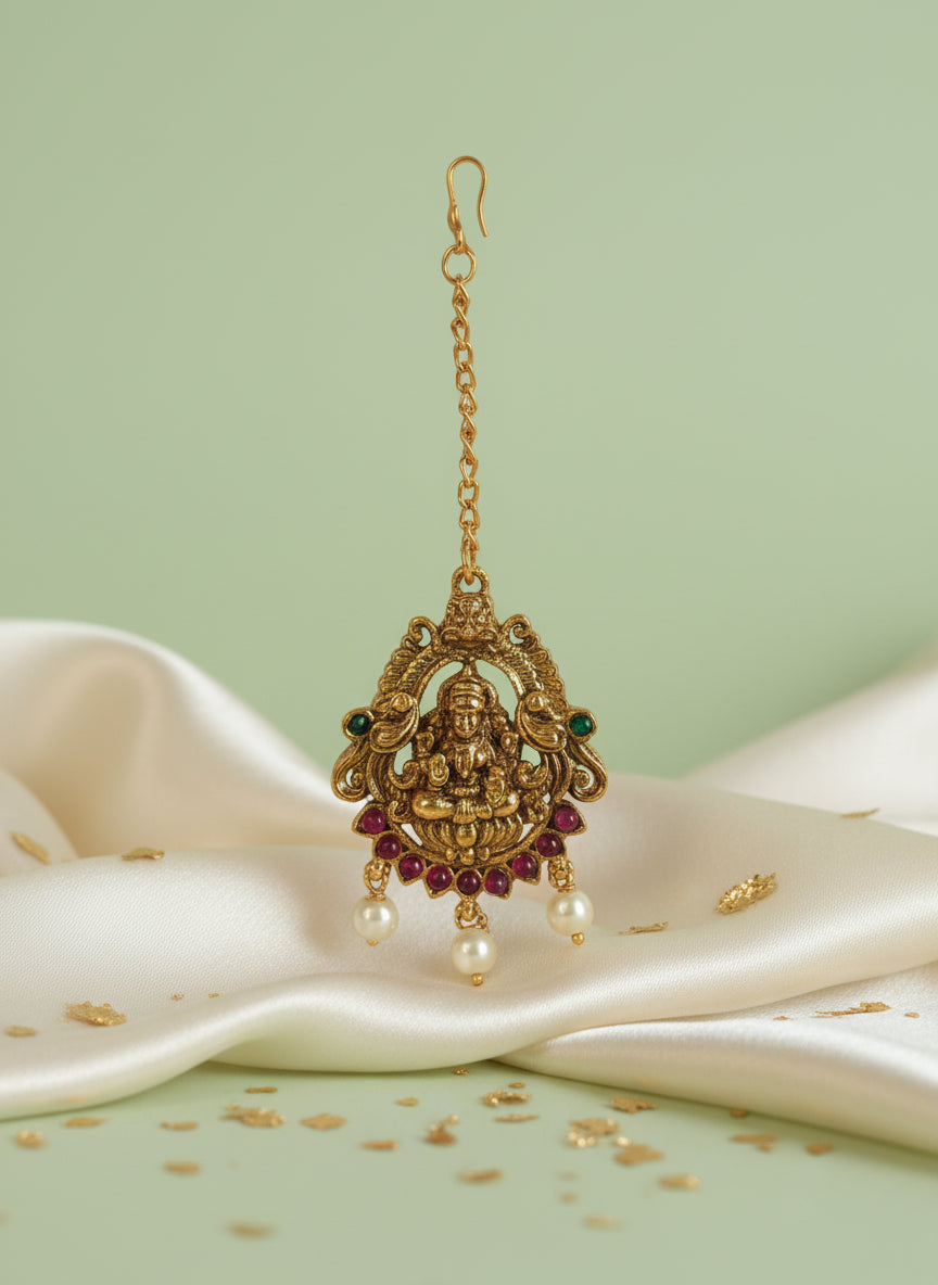 Gold earrings with intricate design and pearls on a light green background
