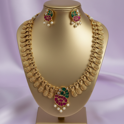 Gold necklace and earrings on a gold mannequin bust with a purple background
