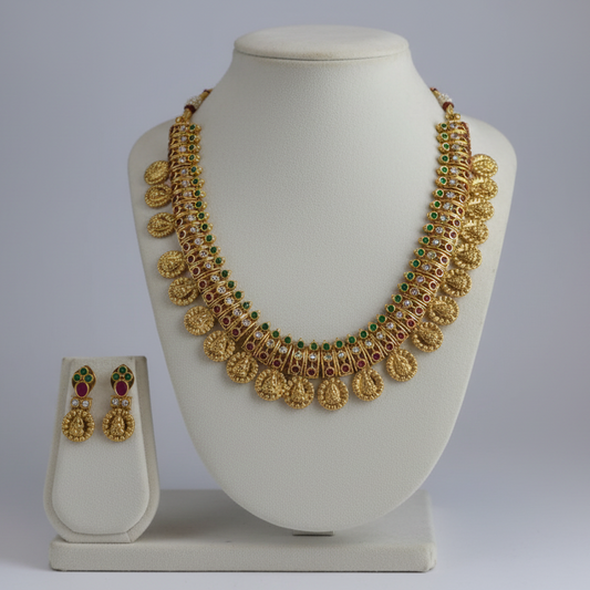Gold necklace and earrings set on a white mannequin bust with a plain background