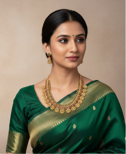 Woman wearing a green saree with gold jewelry on a beige background