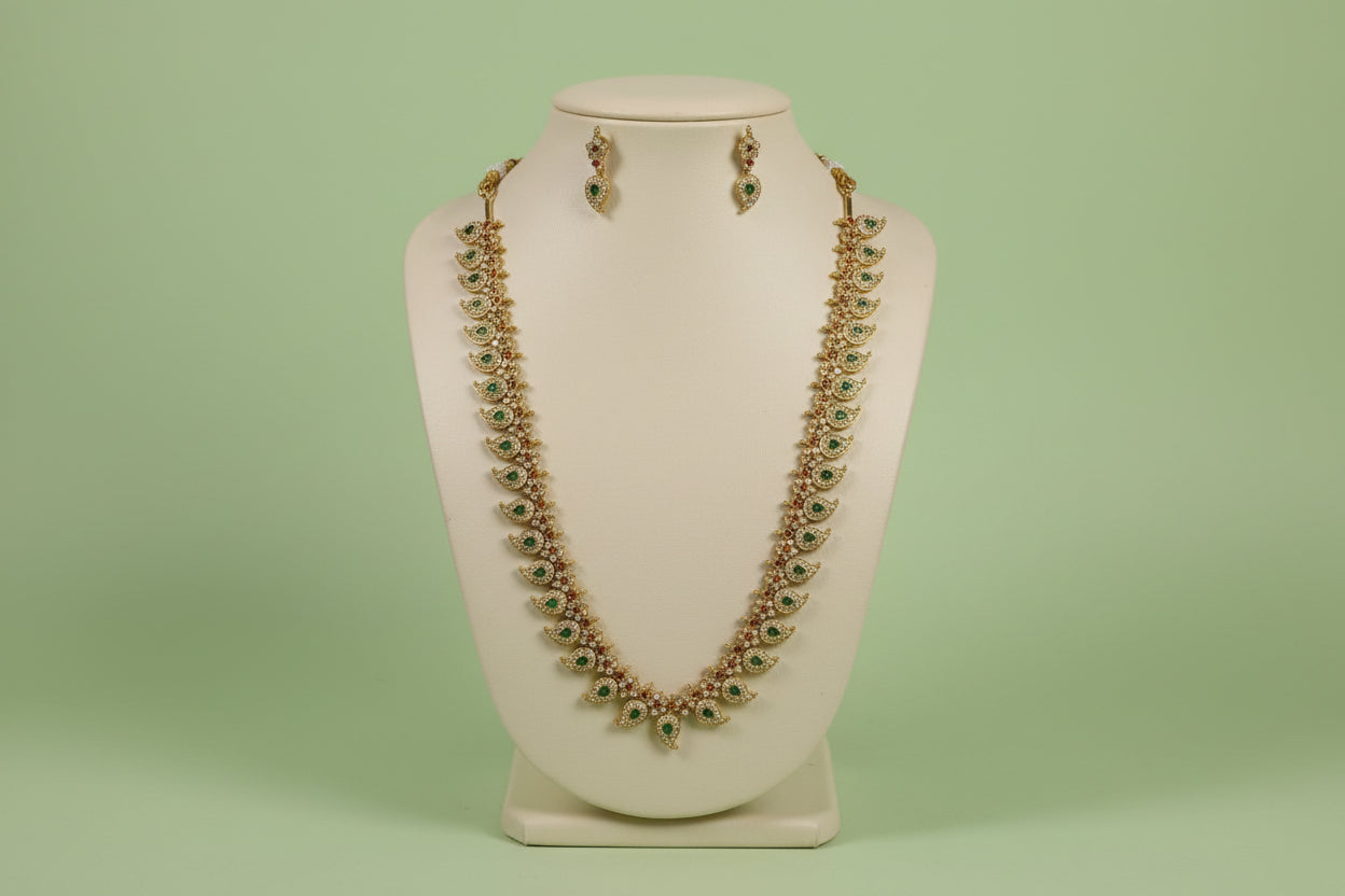 Jewelry set with necklace and earrings on a mannequin bust against a green background