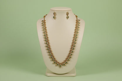 Jewelry set with necklace and earrings on a mannequin bust against a green background