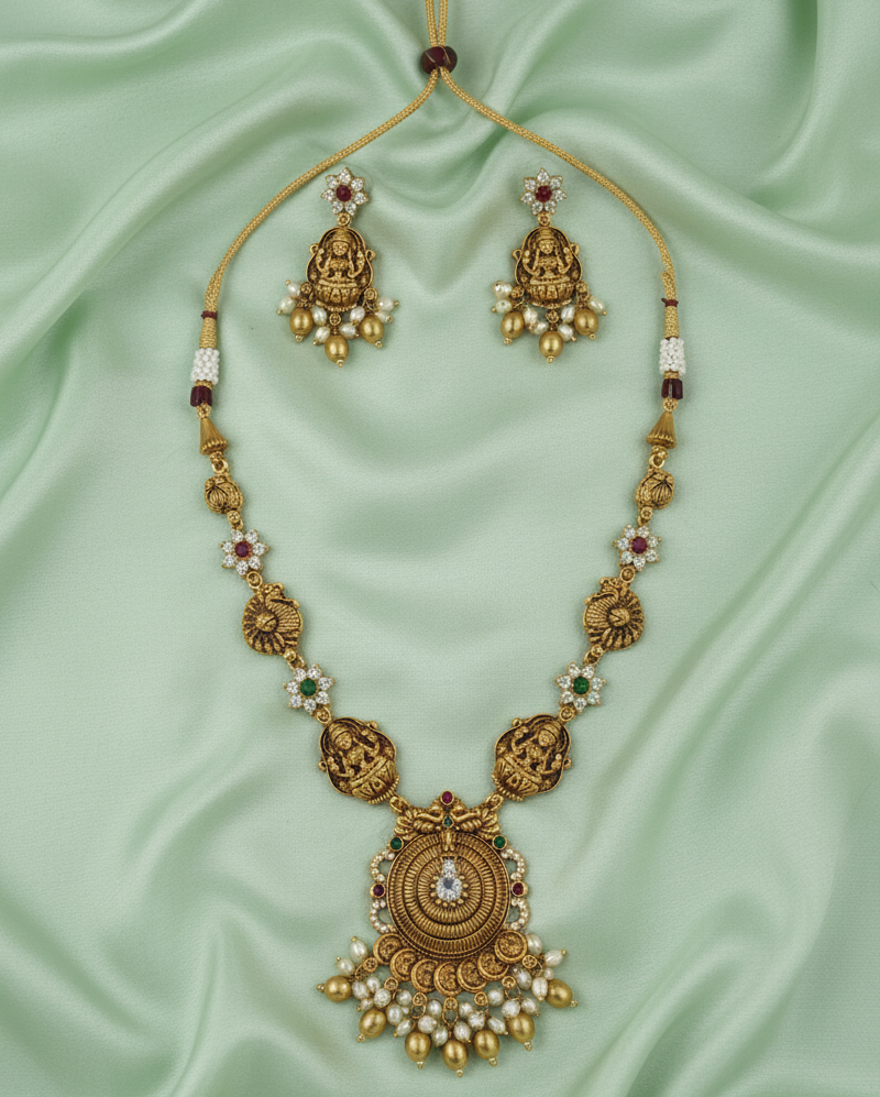 Gold necklace with matching earrings on a light green fabric background