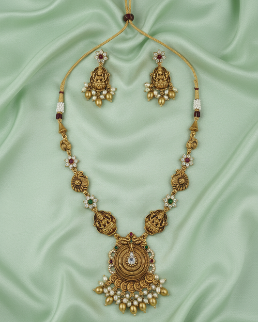 Gold necklace with matching earrings on a light green fabric background