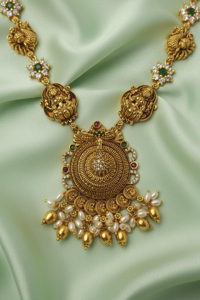 Gold necklace with intricate design and pearl-like beads on a white background