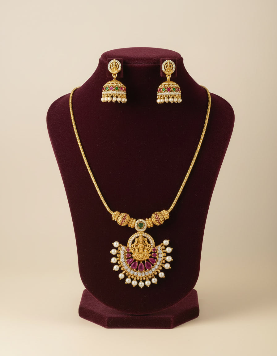 Gold necklace with pendant and matching earrings on a mannequin bust.