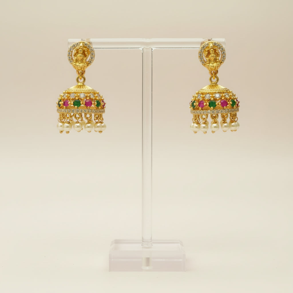 Gold earrings with colorful gemstones on a beige background