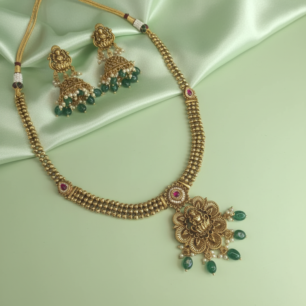 Gold necklace with green gemstones on a light green satin background