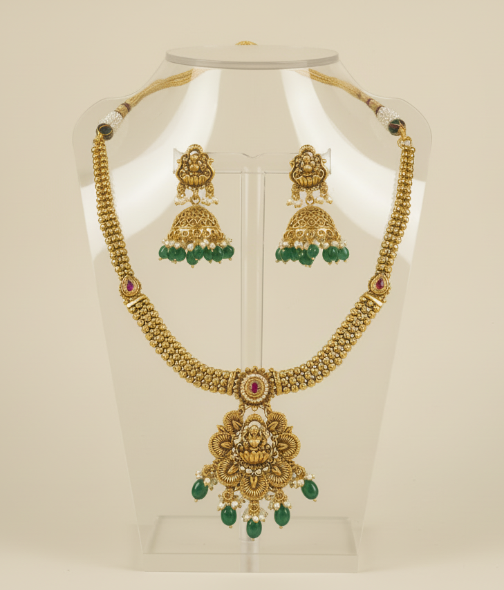 Gold necklace and earrings on a mannequin bust with a beige background